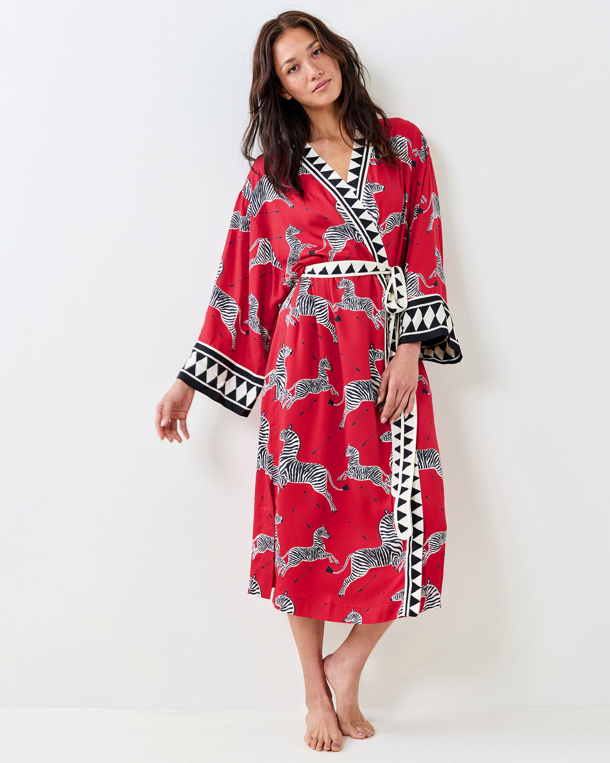 Front view of a person wearing a red zebra-print robe with a tied waist belt and geometric trim.