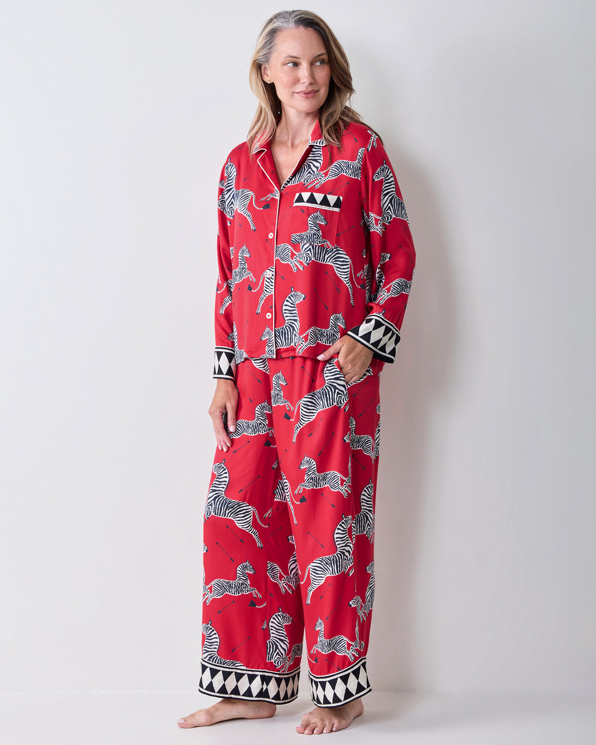 Front view of a person wearing a red zebra-print pajama shirt and wide-leg pants, barefoot.