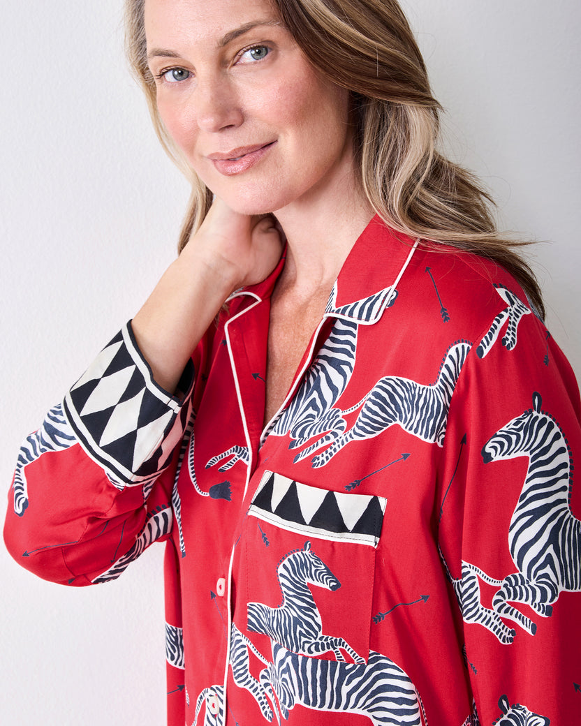Close-up of the red zebra-print pajama shirt showing the collar, button placket, chest pocket, and geometric-trim cuff.