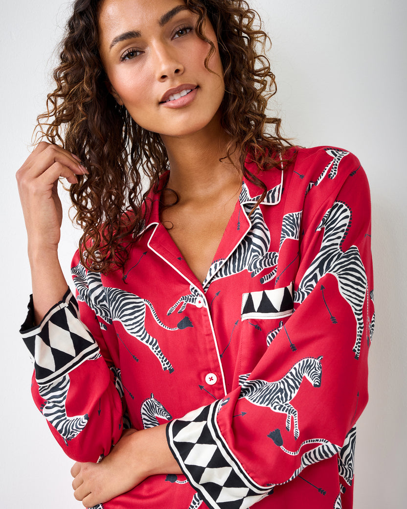 Close-up of the red zebra-print pajama shirt showing the collar, chest pocket, buttons, and geometric-trim cuff.