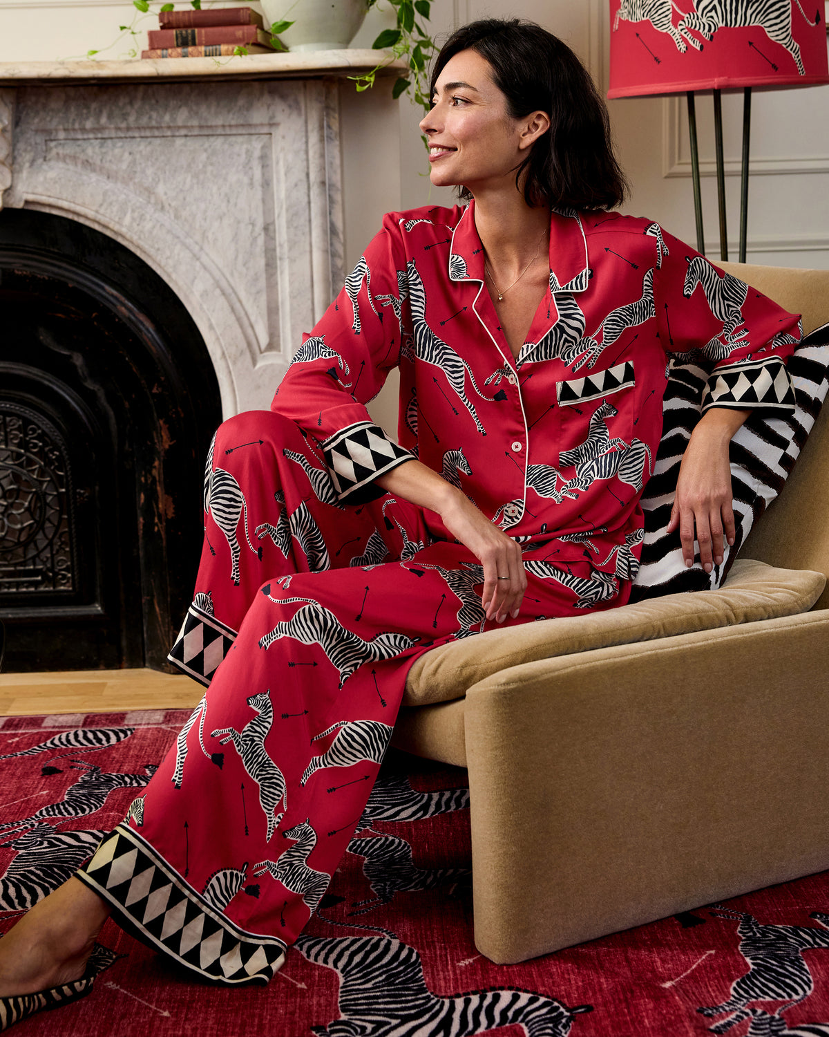 Person seated in the red zebra-print shirt and wide-leg pants from the Eco Satin Soho Set.