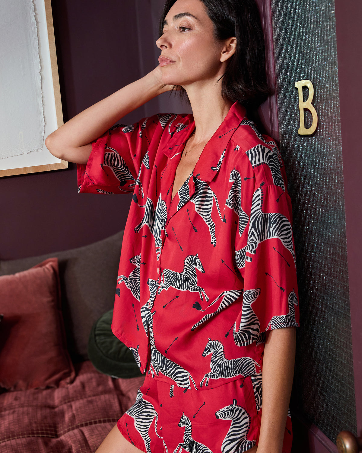 Person wearing the red zebra-print top and shorts from the Eco Satin Sweet Dreams Set, shown seated in profile.