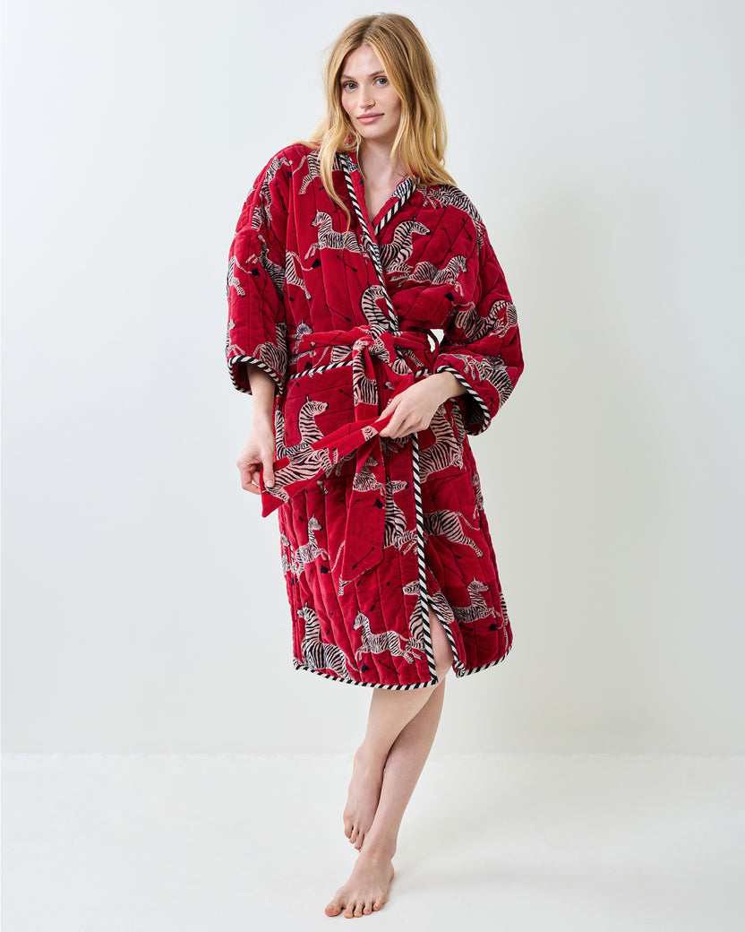 Front view of a person wearing a red zebra-print quilted robe with a belt and pockets.
