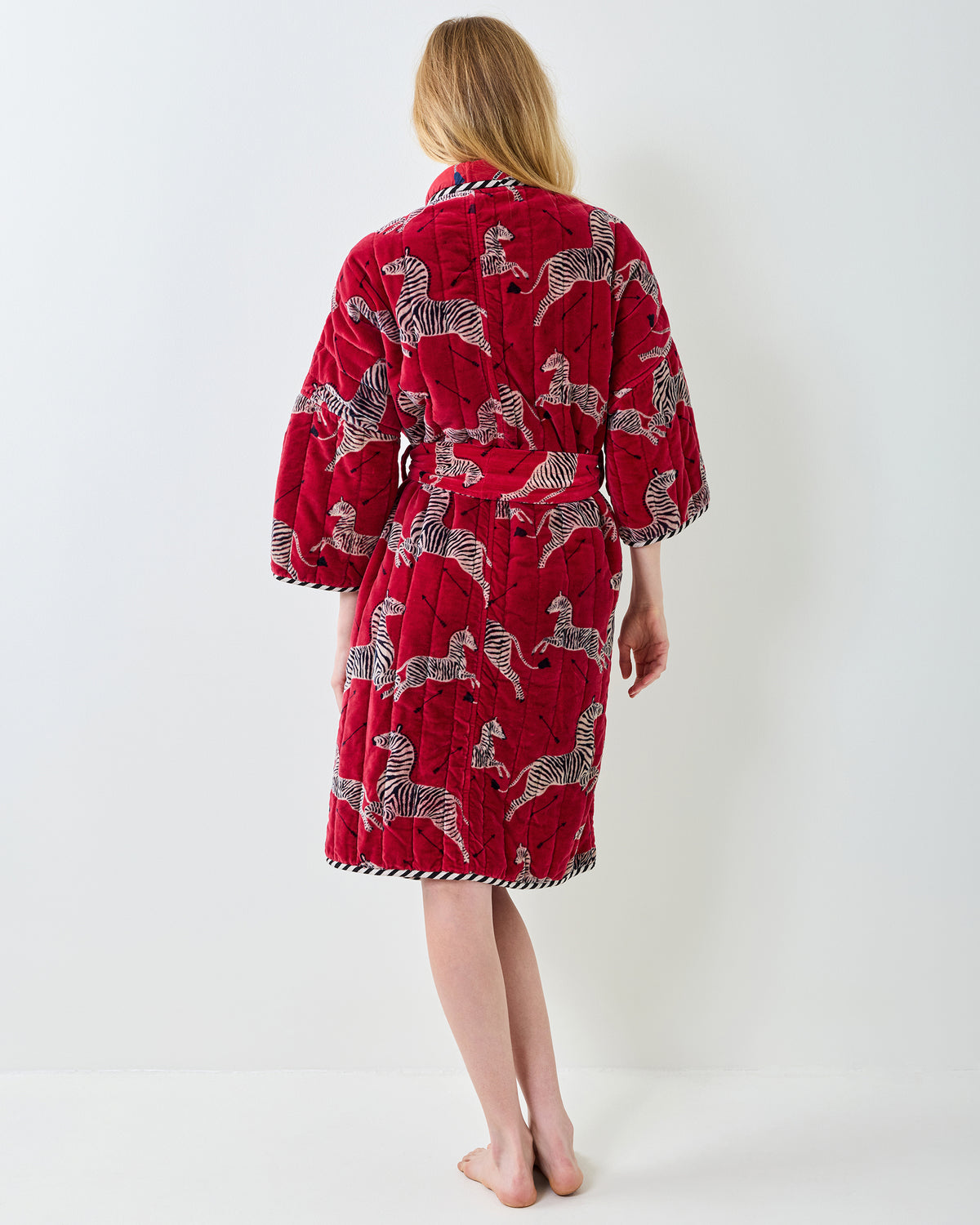 Back view of a red zebra-print quilted robe with a belt and contrasting trim.
