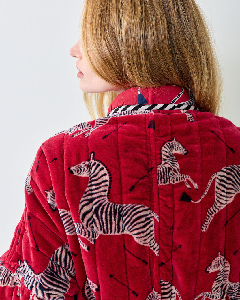 Close-up of the red zebra-print quilted robe showing the collar, back seam, and sleeve.