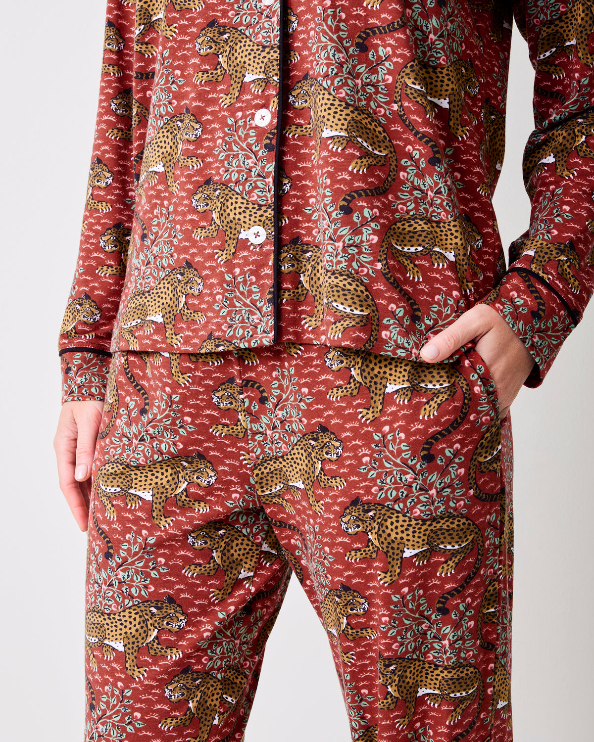 Close-up of the scarlet Bagheera long pajama set showing the button-front top, matching pants, side pocket, and leopard-and-leaf print.