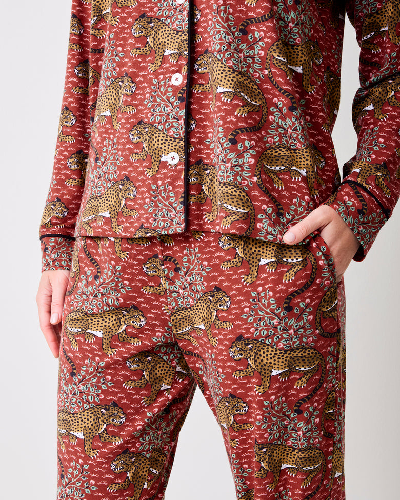 Close-up of the scarlet Bagheera long pajama set showing the button-front top, matching pants, side pocket, and leopard-and-leaf print.