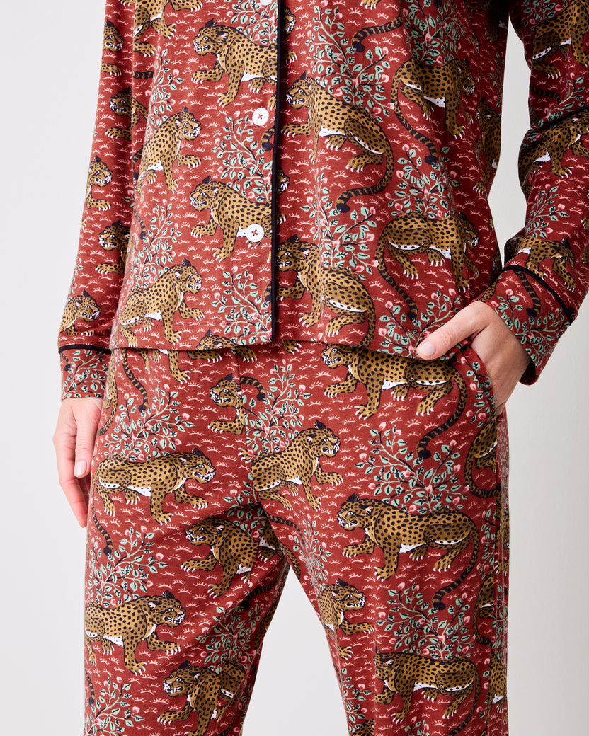 Close-up of the scarlet Bagheera long pajama set showing the button-front top, matching pants, side pocket, and leopard-and-leaf print.