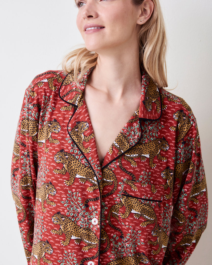 Close front view of the Scarlet Bagheera long-sleeved sleep shirt with a leopard and botanical print, notched collar, black piping, buttons, and chest pocket.