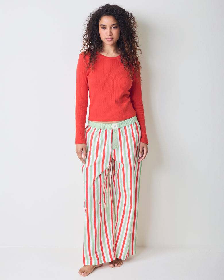 Model wearing Elf Stripes petite Nola pajama pants with vertical sage and cherry stripes, shown from the front.