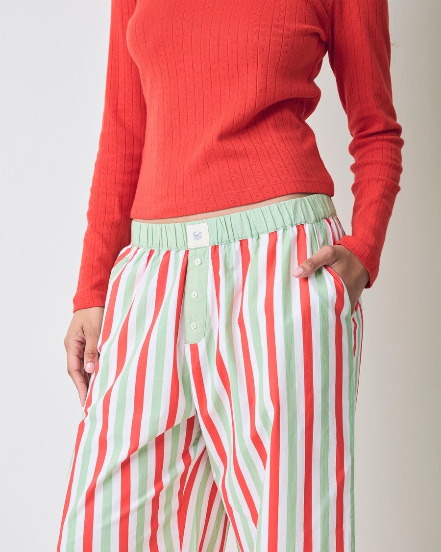 Close view of Elf Stripes Nola pajama pants showing the vertical sage and cherry stripes, elastic waistband, pockets, and button-front fly.