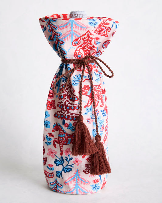 Printed wine bag standing upright with a bottle visible at the top and brown braided drawstring ties with tassels.