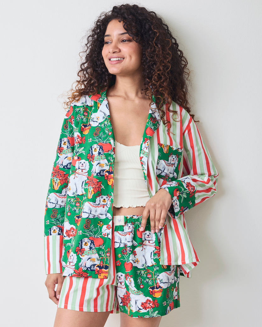 Front three-quarter view of the Good Dog Christmas Reese boxer pajama set with a green dog-and-poinsettia print and striped sleeves and shorts.