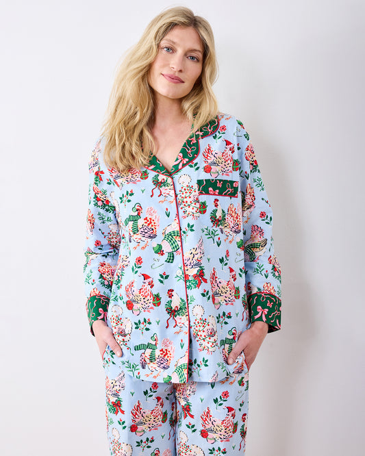Person wearing a pale blue long-sleeve pajama set with a colorful holiday hen print.