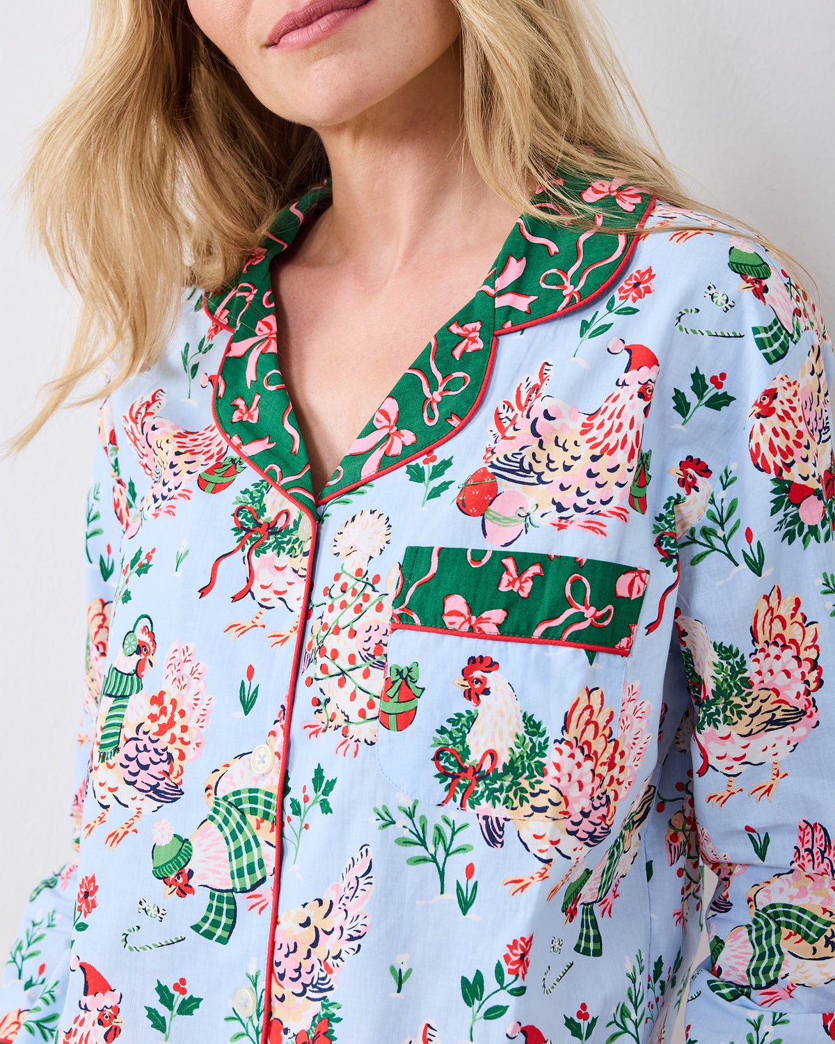 Close-up of the pale blue Holiday Hens pajama top showing the hen print, contrasting collar, button front, and chest pocket.