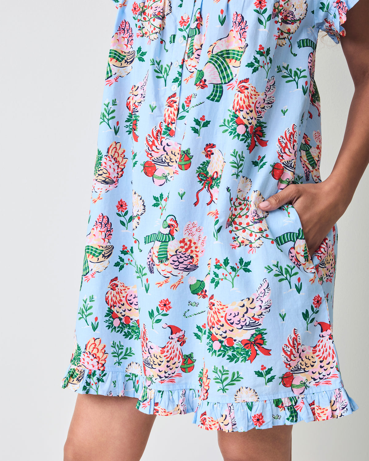 Close-up of the pale blue Holiday Hens nightgown pocket, hen print, and ruffled hem.