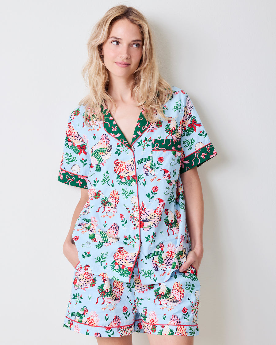 Person modeling a pale blue short pajama set with printed hens, flowers, and green trim.