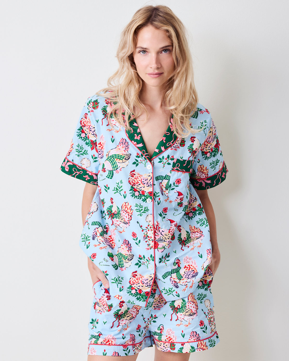 Front view of a person wearing the pale blue Holiday Hens short pajama set with a printed button-down top and shorts.