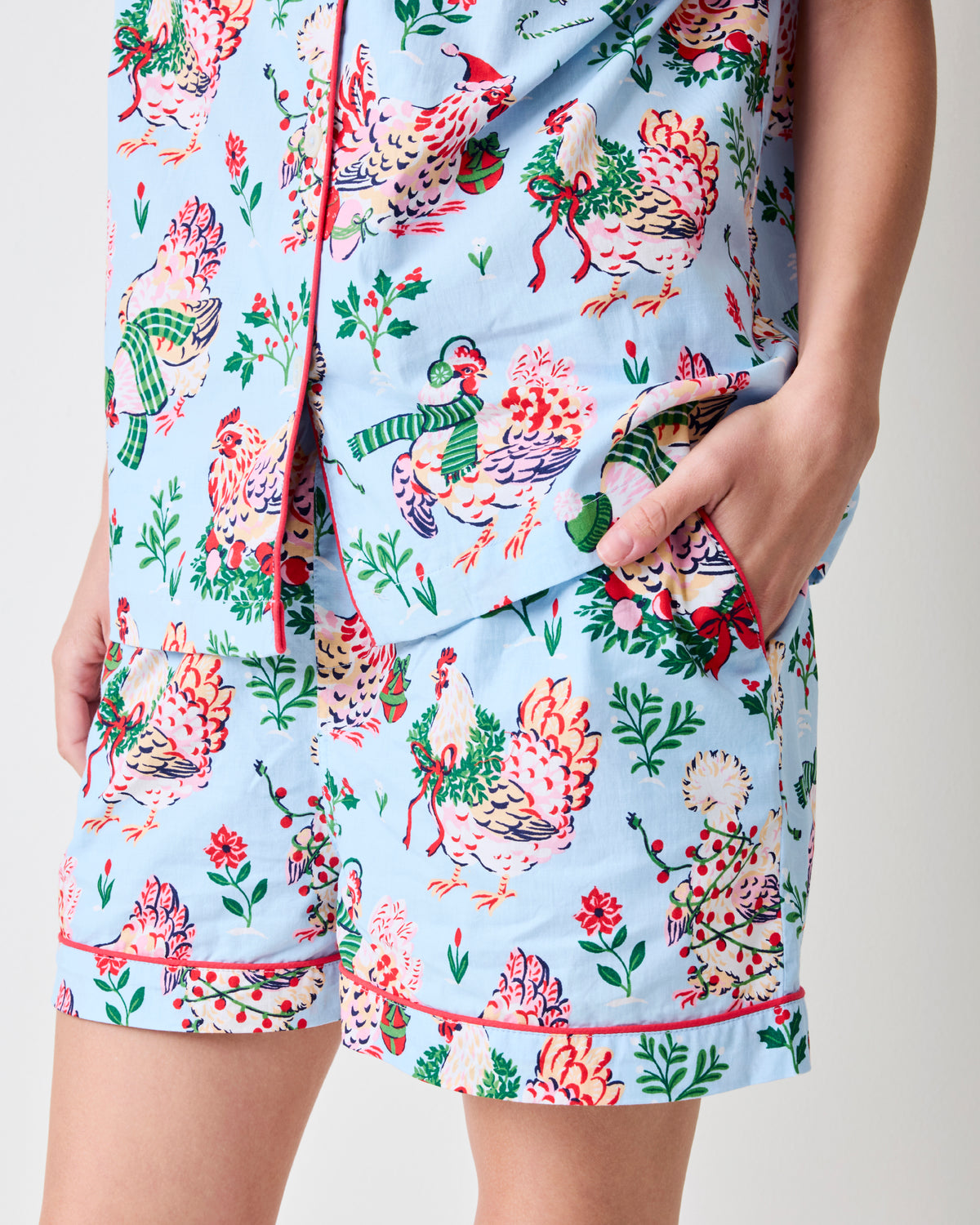 Close-up of the pale blue Holiday Hens short pajama set showing the button-front top, elastic-waist shorts, pockets, and red-trimmed hems.
