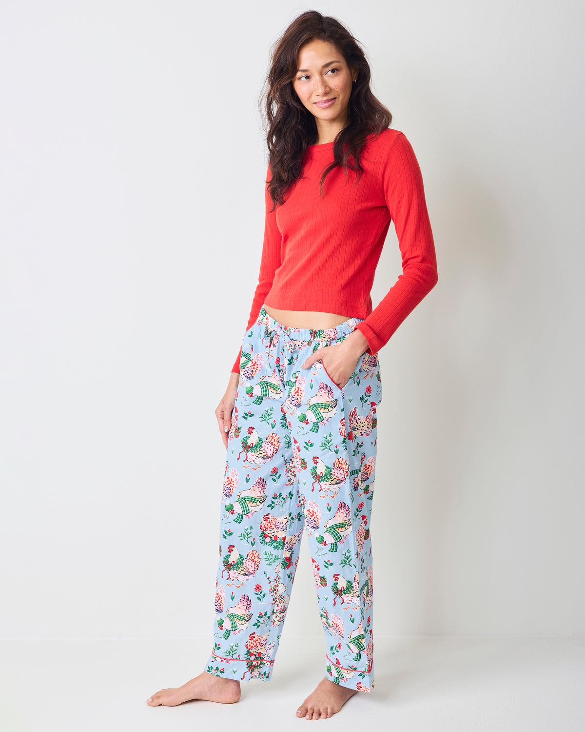 Person wearing pale blue Holiday Hens full-length pajama pants with a repeated hen and floral print.