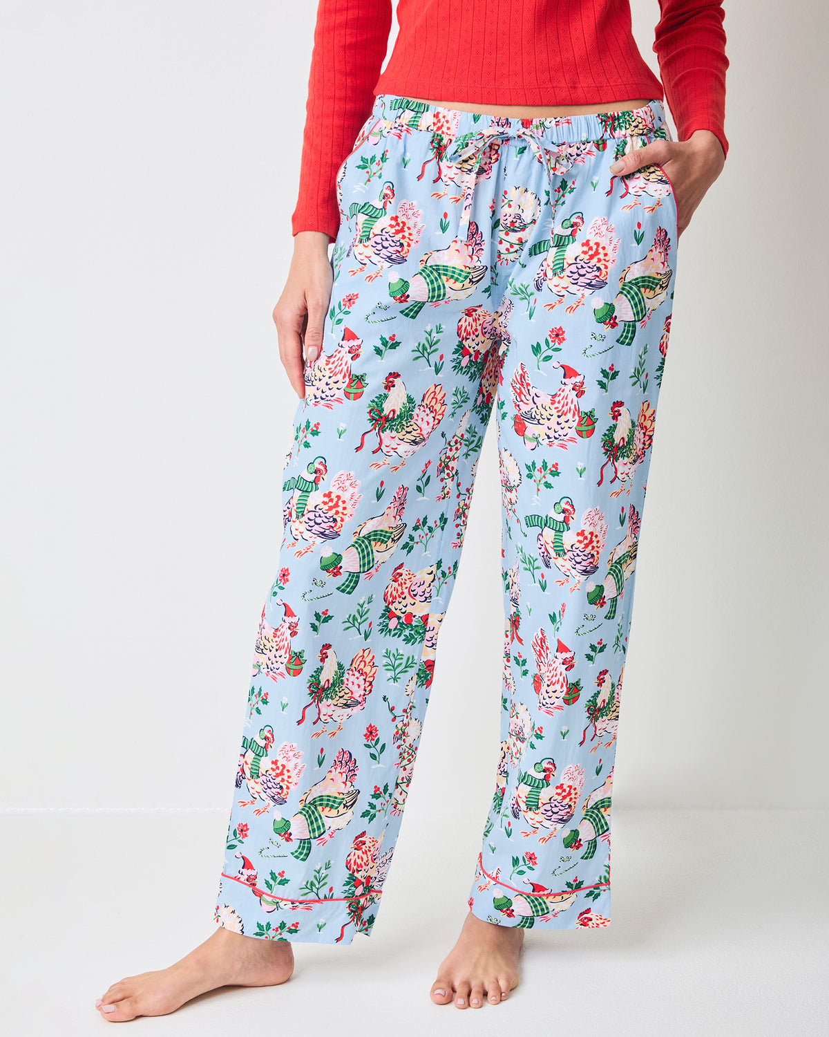 Close-up of pale blue Holiday Hens pajama pants showing the repeated hen print, elastic drawstring waistband, and side pockets.