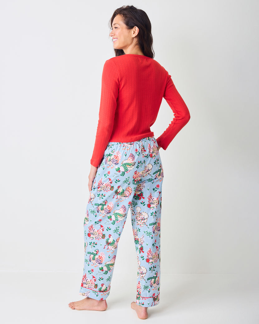 Back view of a person wearing pale blue Holiday Hens full-length pajama pants with a repeated hen and floral print.