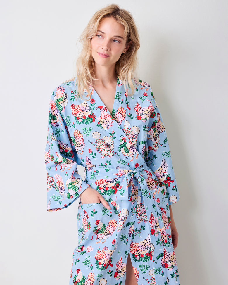 Close view of the pale blue Holiday Hens robe showing its floral hen print, wrap front, belt, long sleeves, and side pocket.