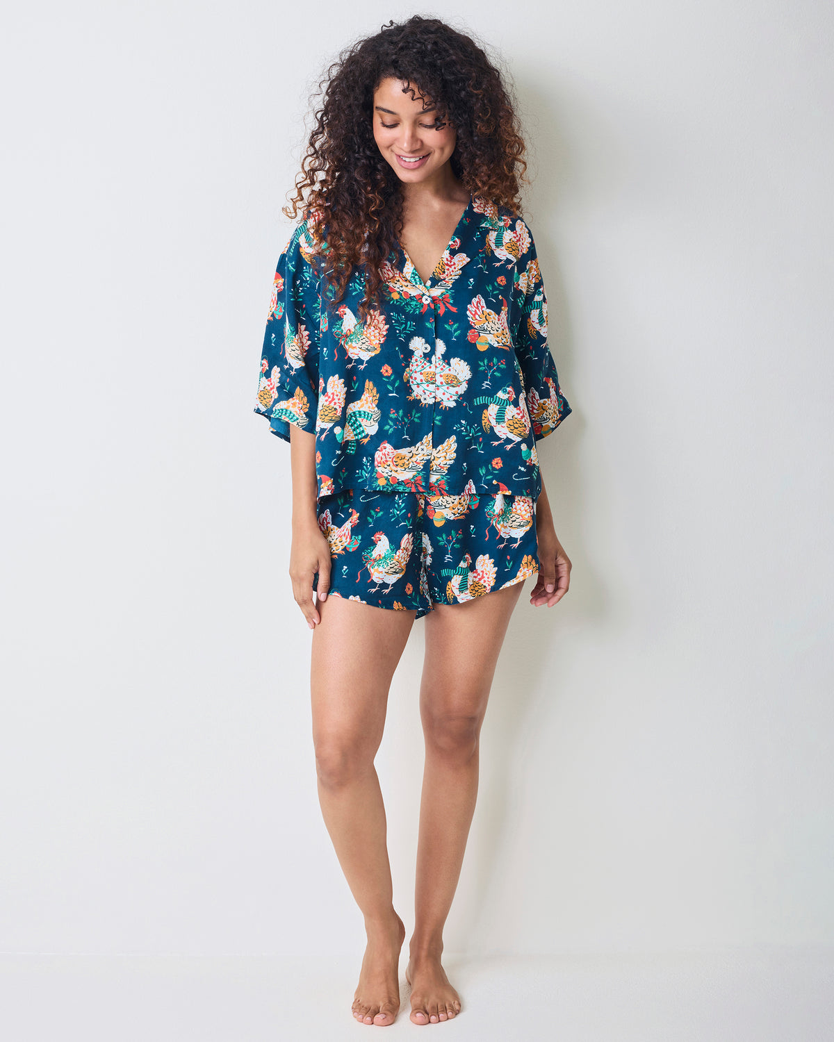 Full-length front view of a model wearing the Holiday Hens pajama set with a loose top and matching shorts.