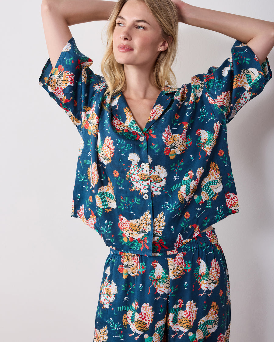 Cropped front view of the navy Holiday Hens pajama set, showing the short-sleeved button-front top and wide-leg pants with a chicken print.
