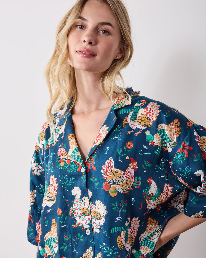 Close front view of the navy Holiday Hens pajama top, showing its notched collar, buttons, short sleeves, and chicken print.