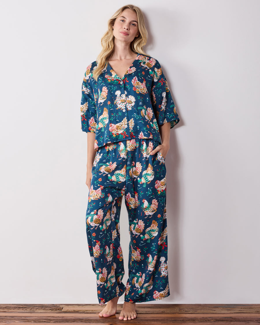 Full-length front view of the navy Holiday Hens pajama set with a button-front top, wide-leg pants, and all-over chicken print.