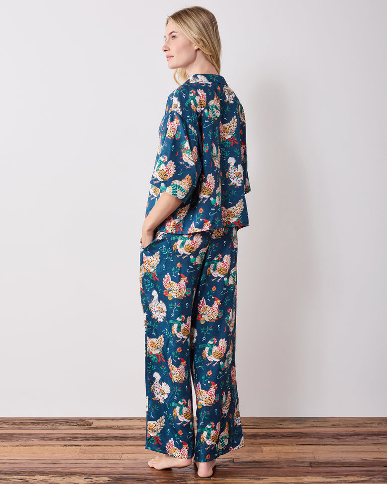 Back three-quarter view of the navy Holiday Hens pajama set, showing the printed back of the top and wide-leg pants.