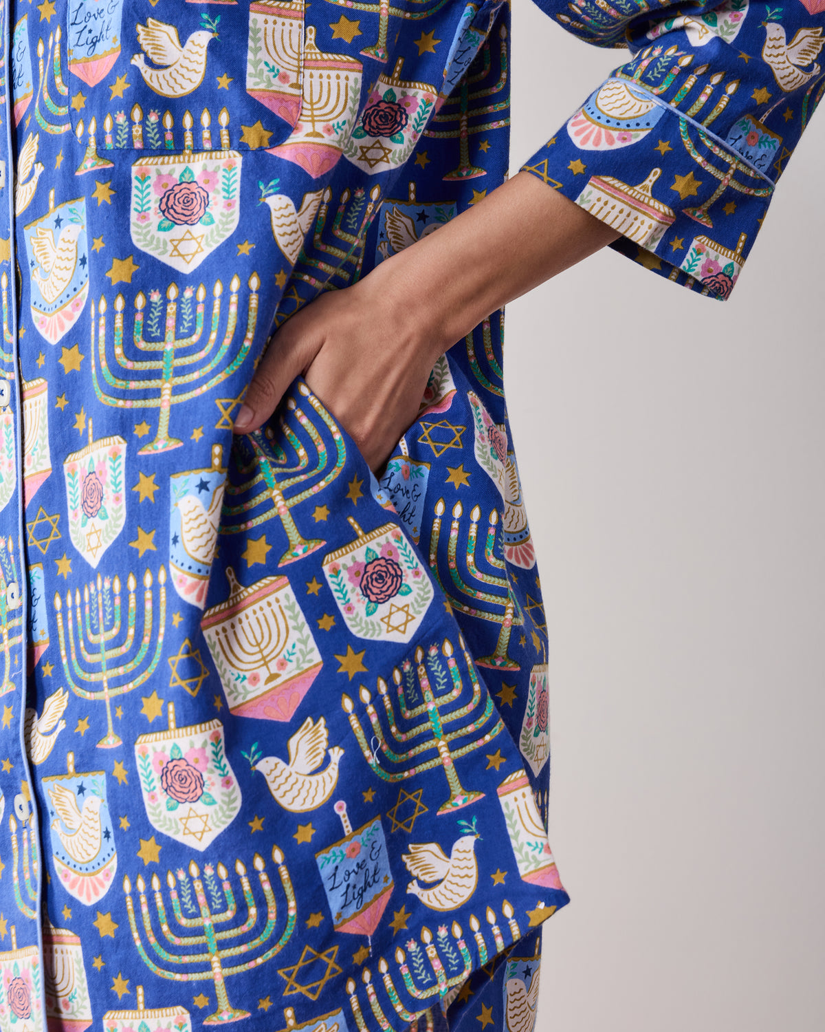 Close-up of the blue patterned sleep shirt showing a side pocket, long sleeve cuff, and curved hem.