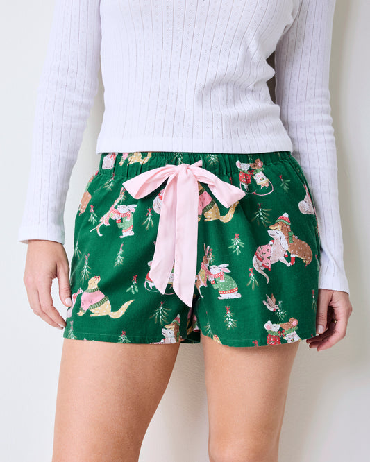 Close front view of green printed pajama shorts with a pink waist tie and illustrated holiday animal print.