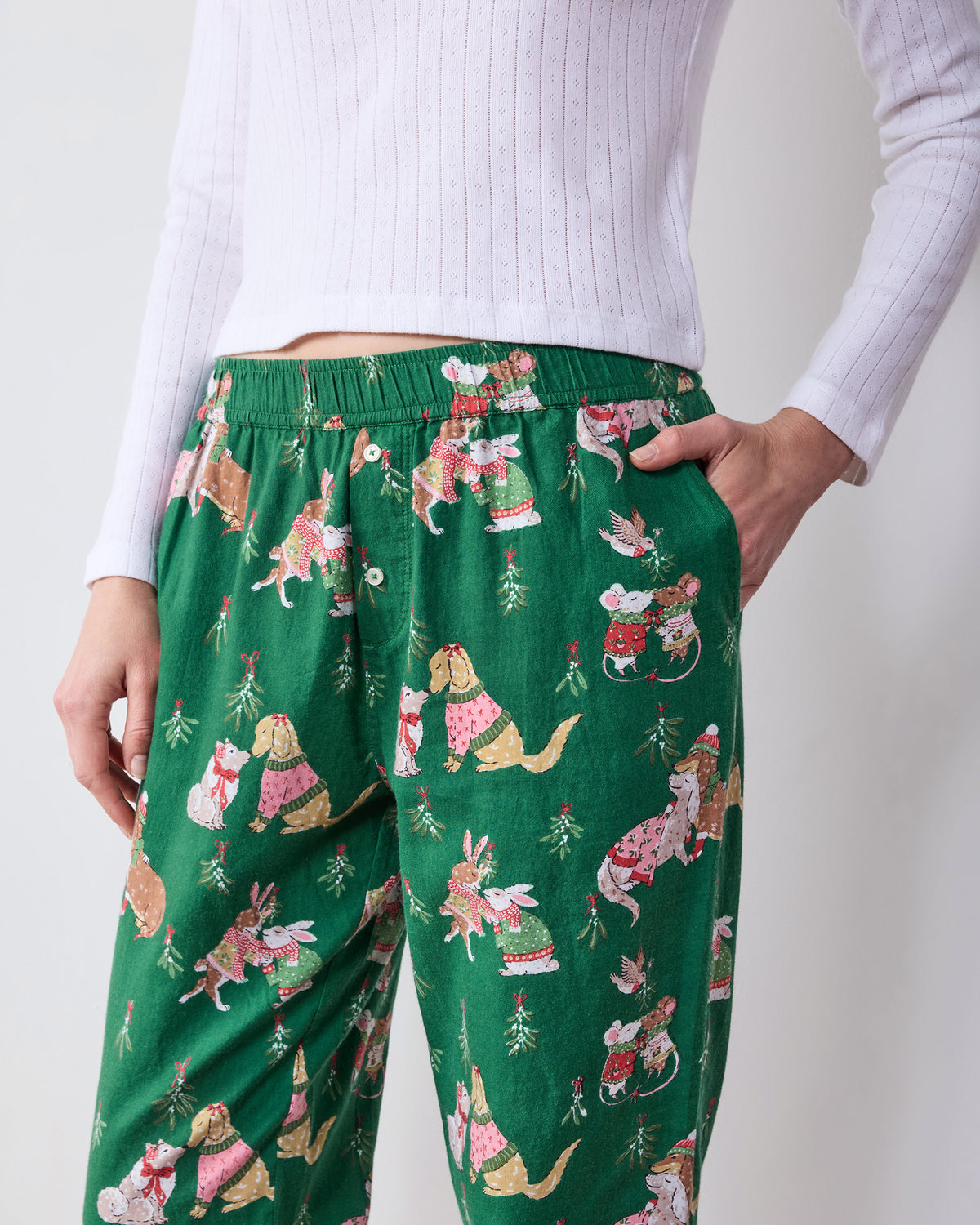 Close front view of green printed joggers showing the elastic waistband, drawstring, buttoned fly, and side pockets.