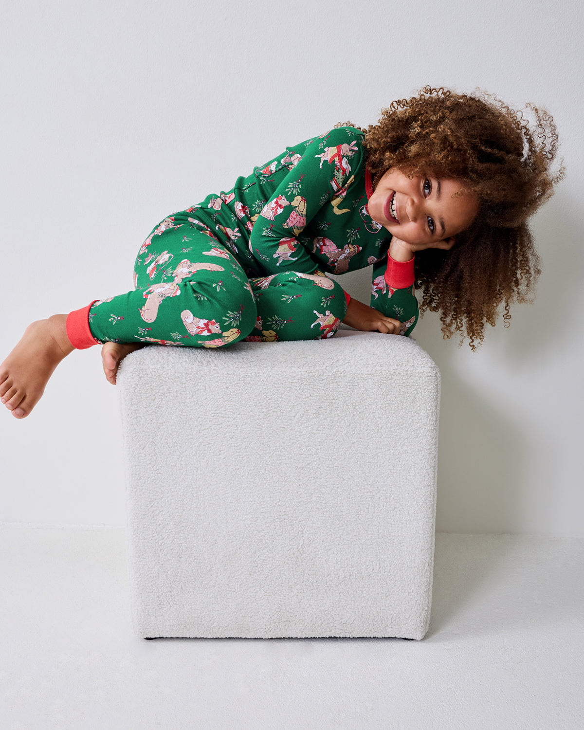 Person in green printed pajamas reclining on a light upholstered ottoman.