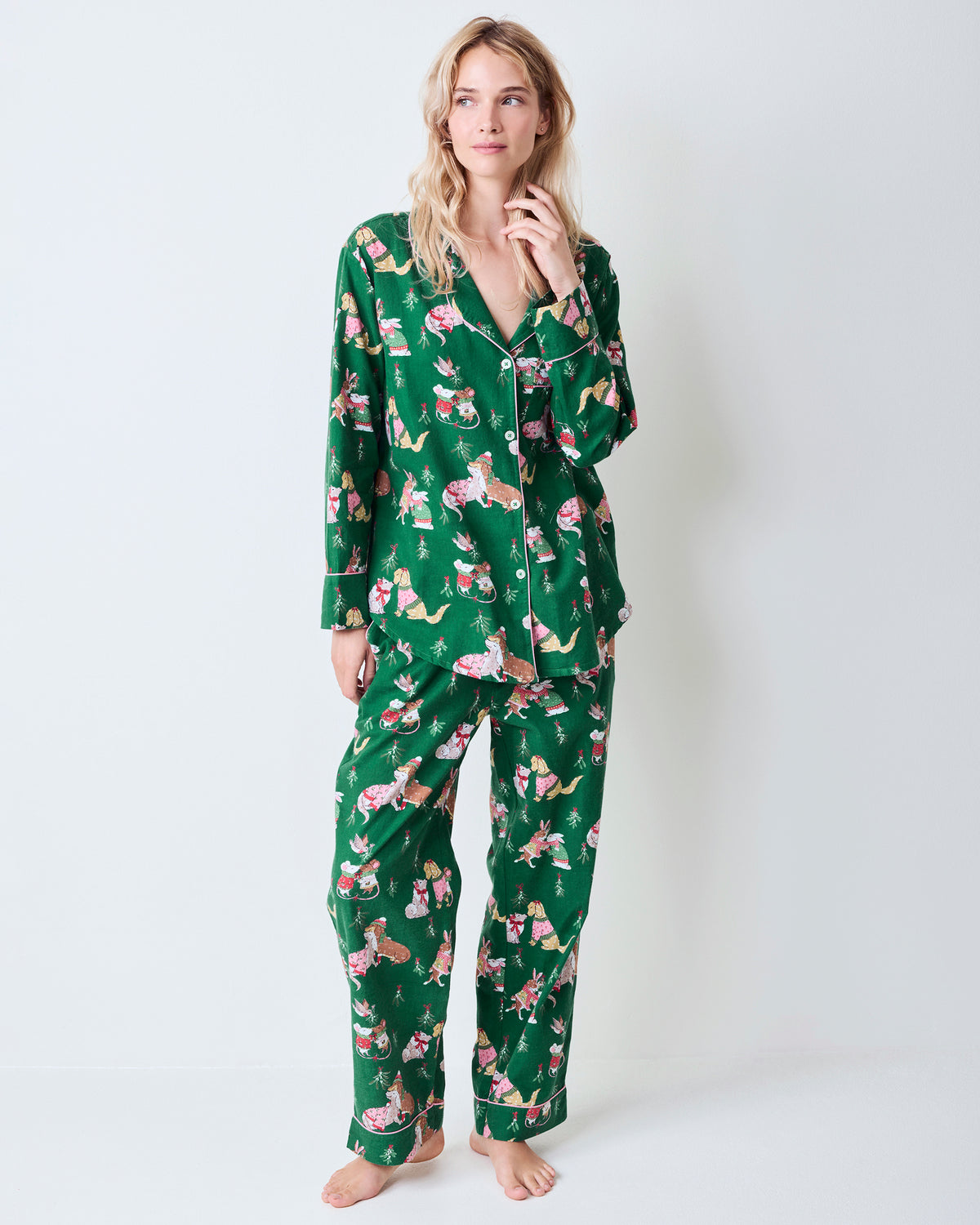 Front view of the green Mistletoe Kiss flannel pajama set with a button-down top, matching pants, pockets, and a holiday critter print.