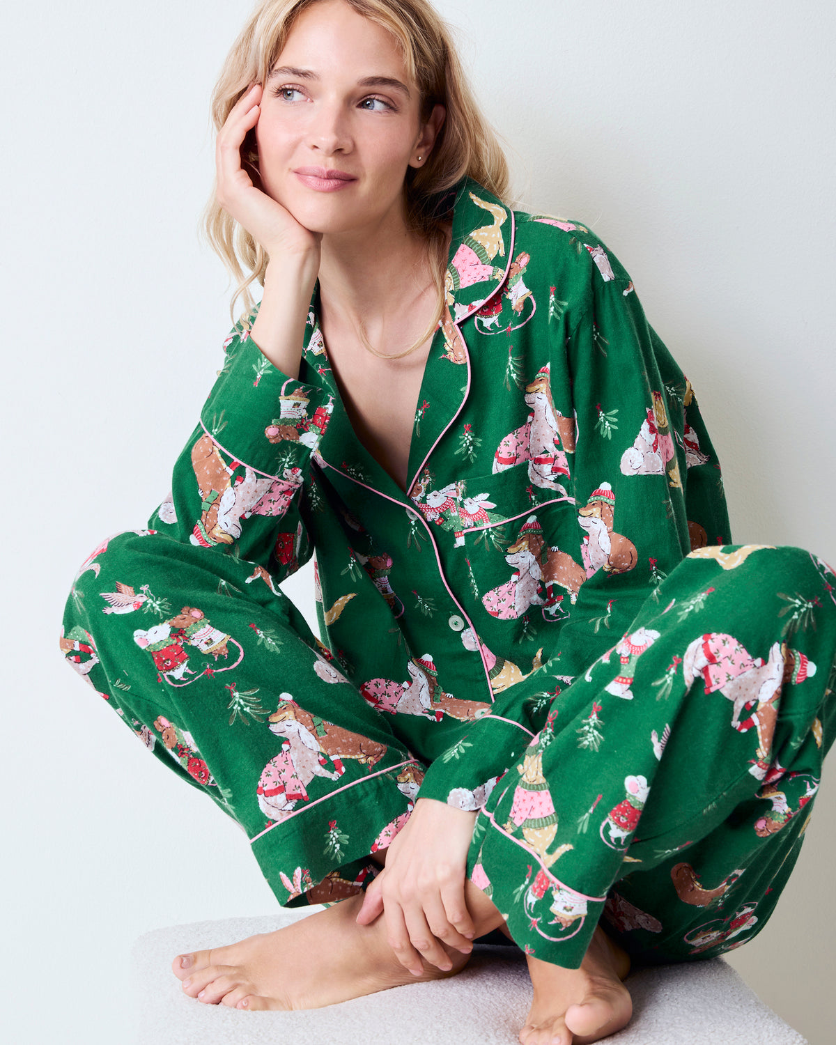 Close seated view of the green Mistletoe Kiss flannel pajama set, showing the piped collar, sleeves, and printed pants.