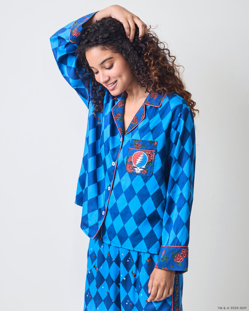 Three-quarter front view of the blue argyle pajama shirt with rose-patterned collar and cuffs, pink piping, buttons, and skull-and-lightning chest pocket.