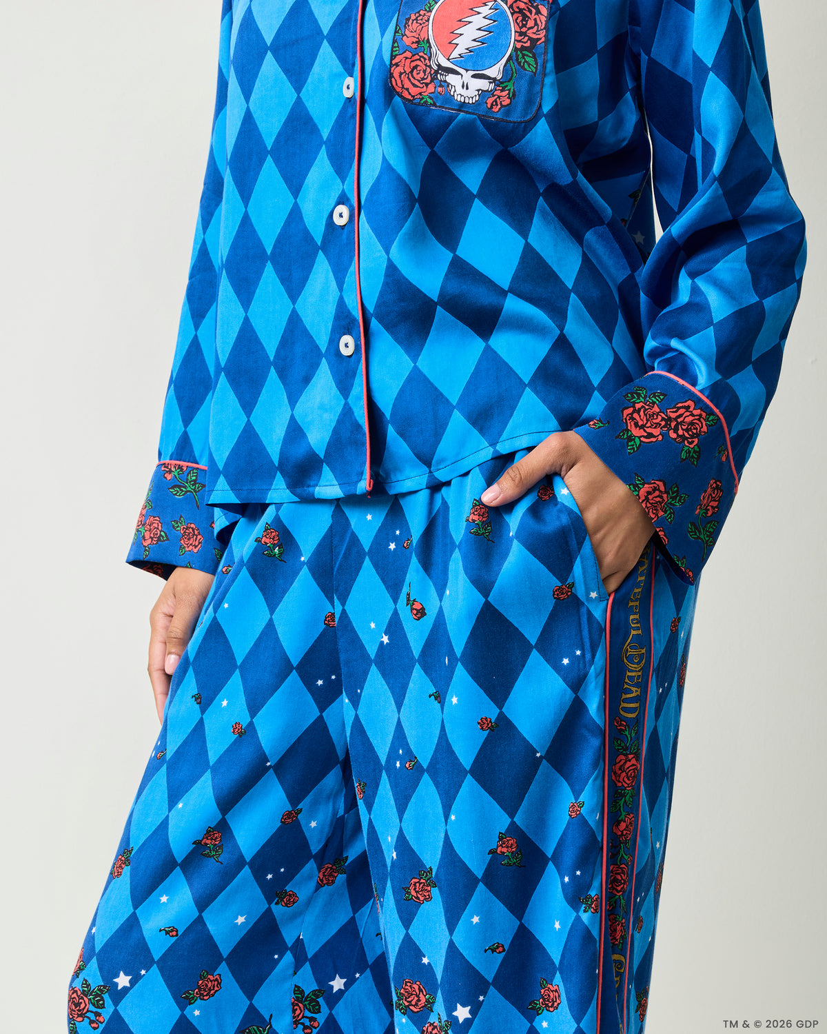 Close-up of the blue argyle pajama shirt, rose-trimmed cuff, side pocket, and matching pants with rose and star accents.