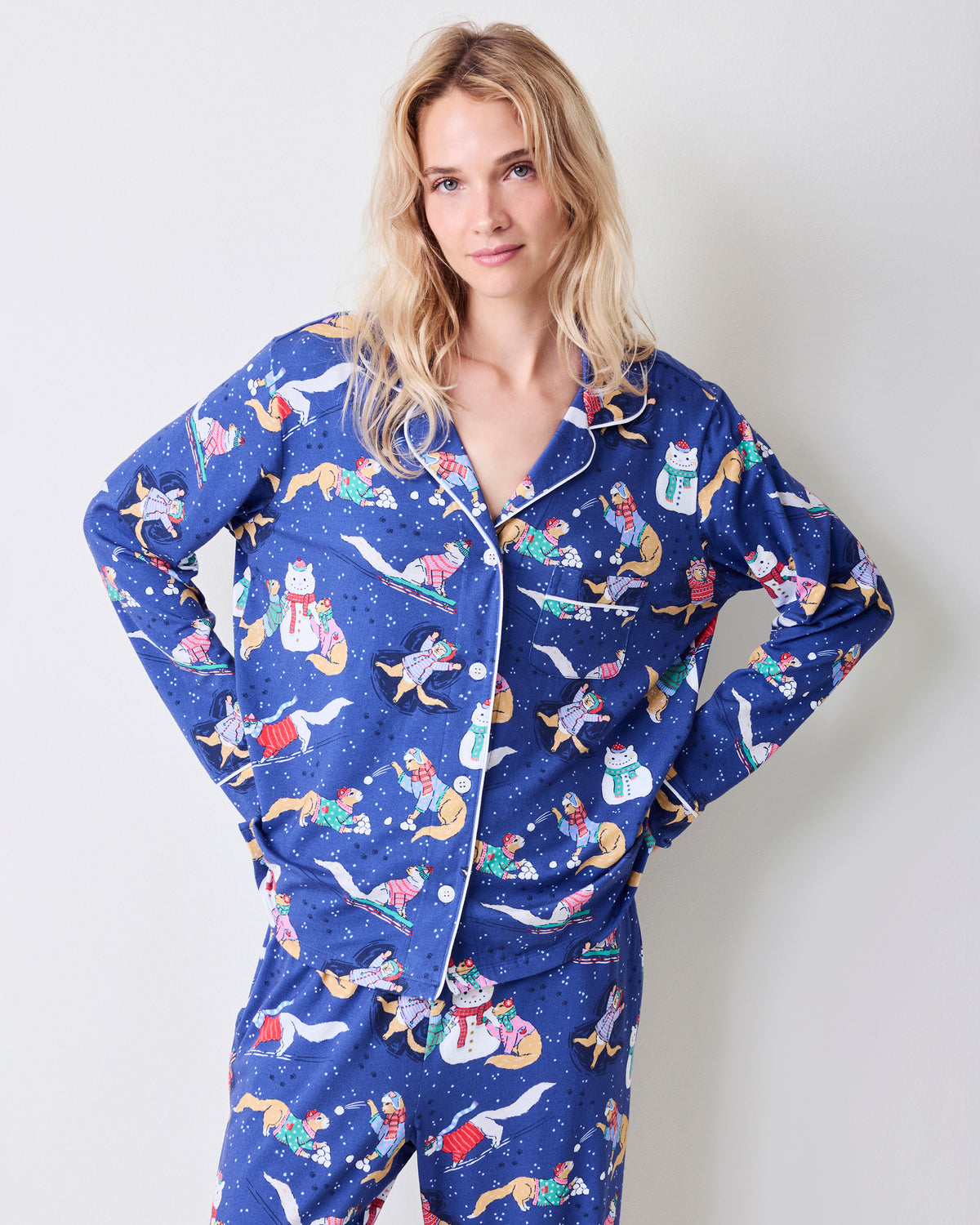 Close view of the blue pajama top with white piping, buttons, chest pocket, and winter print.