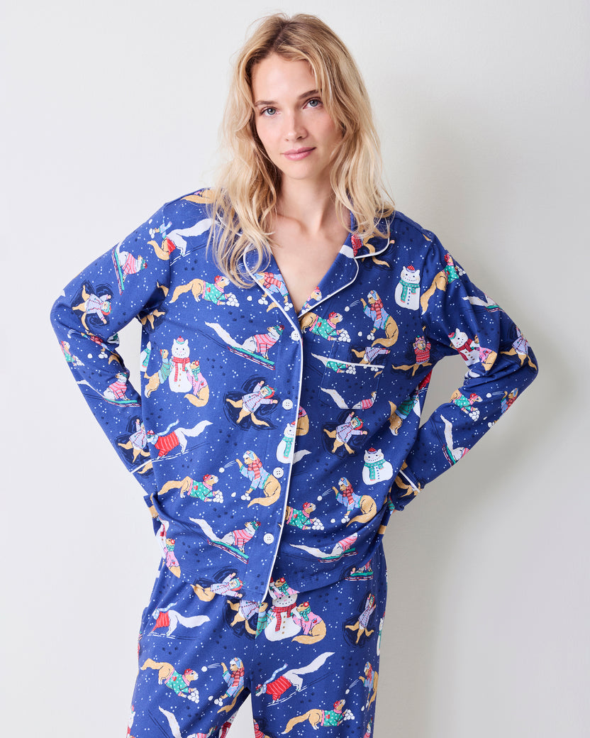 Close view of the blue pajama top with white piping, buttons, chest pocket, and winter print.