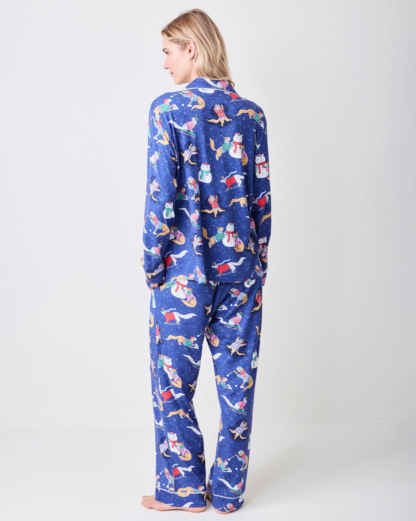 Back view of a model wearing a blue long pajama set with a cat-and-snowman winter print.