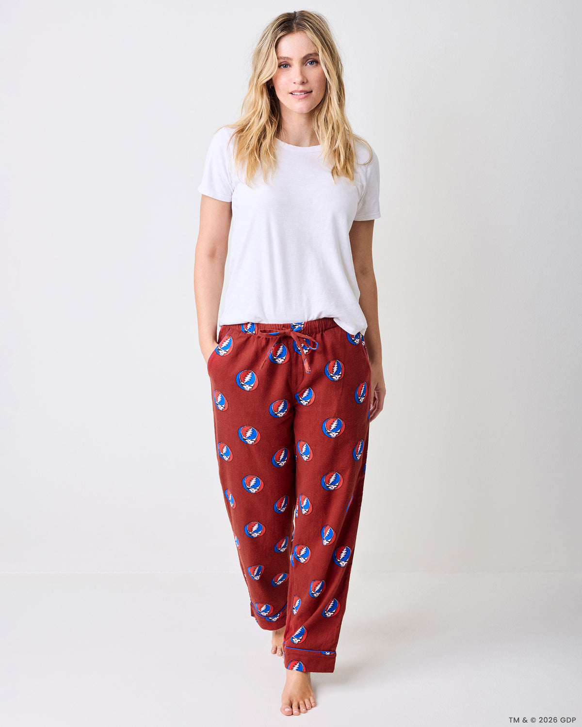 Front view of red full-length pajama pants while walking, with a drawstring waist and skull-and-lightning-bolt print.