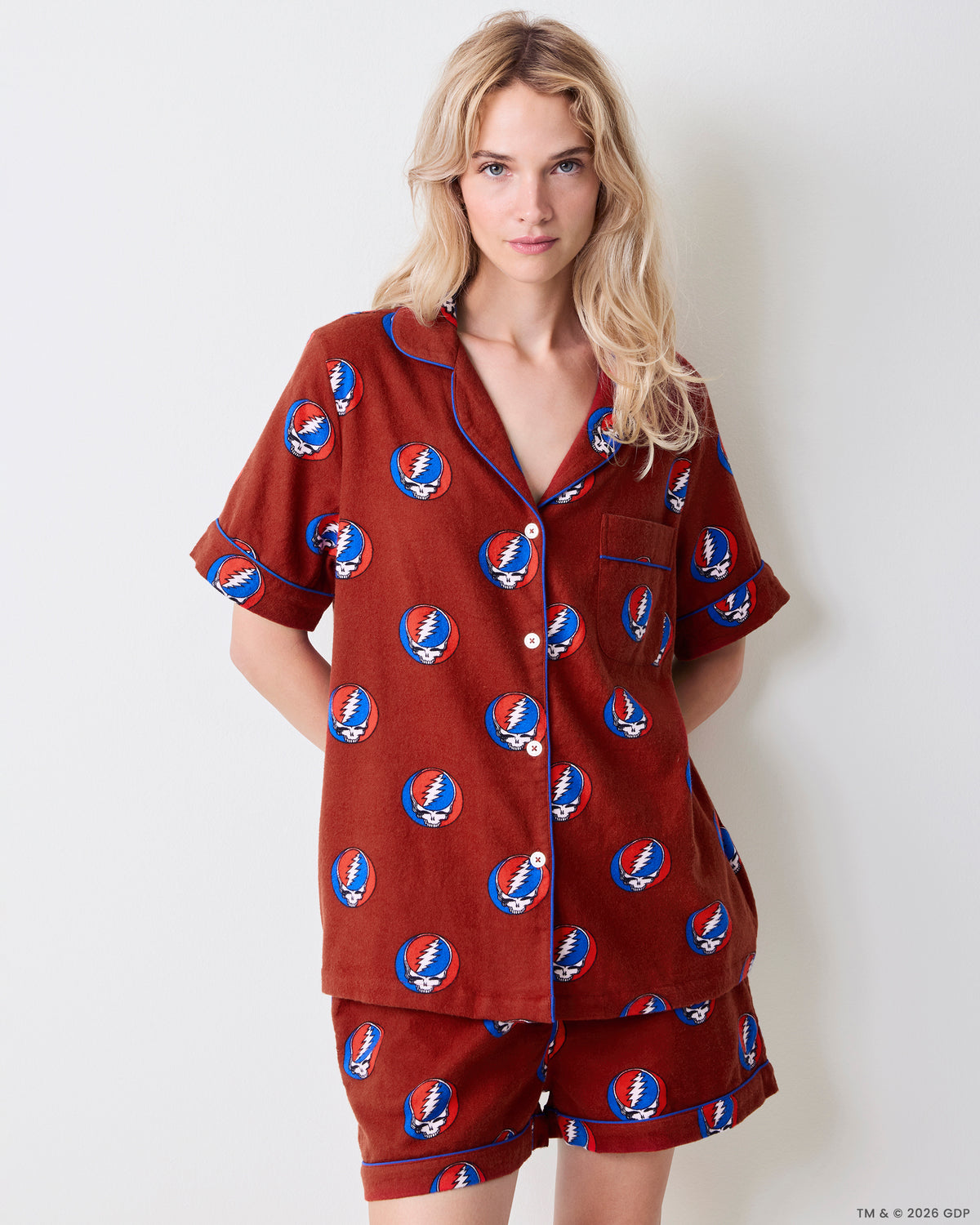 Front studio view of a short-sleeved button-front pajama shirt and matching shorts with blue piping and a skull-and-lightning-bolt print.