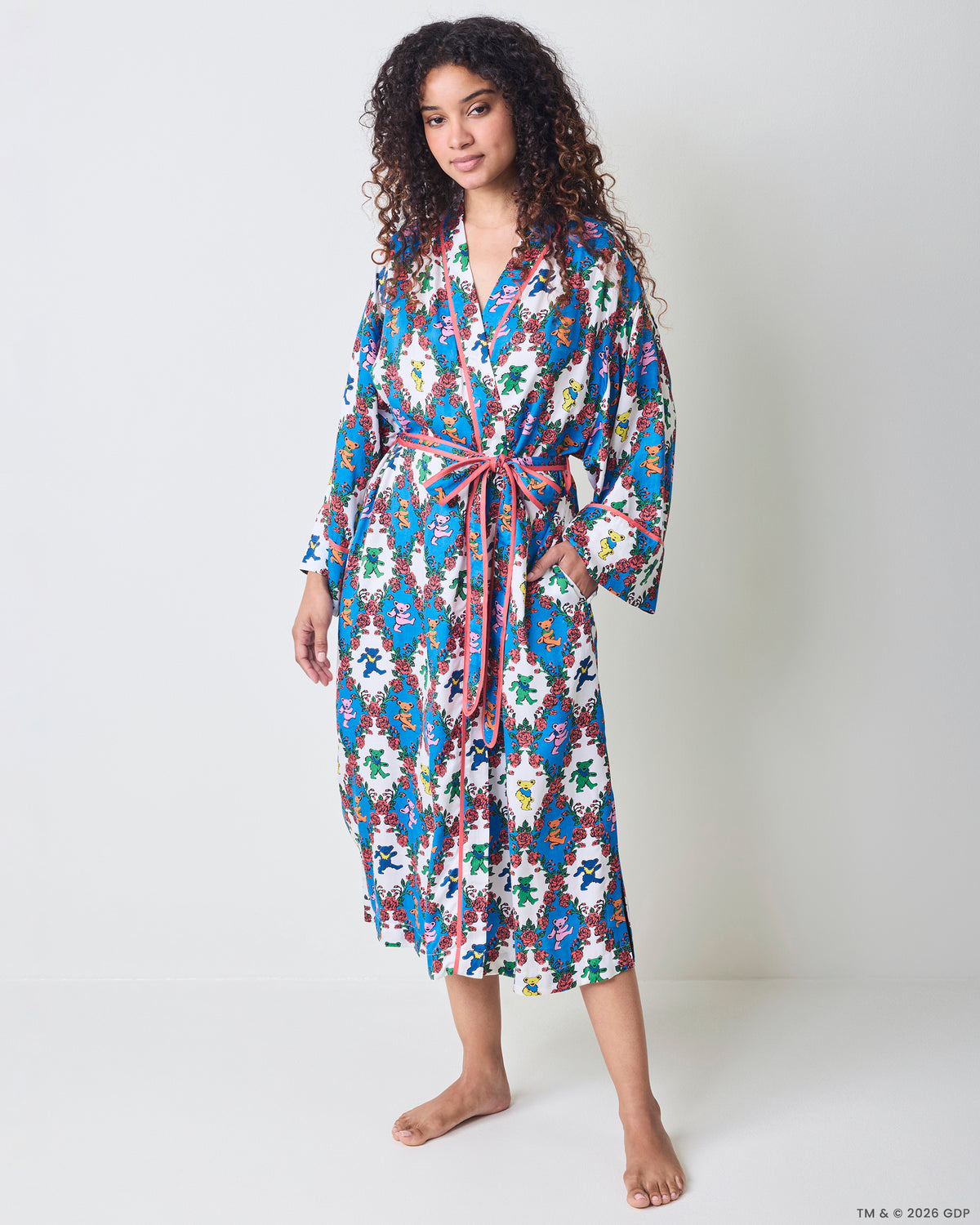 Full front view of a long robe with wide sleeves, pink trim, waist ties, and a blue-and-white bear-and-rose print.