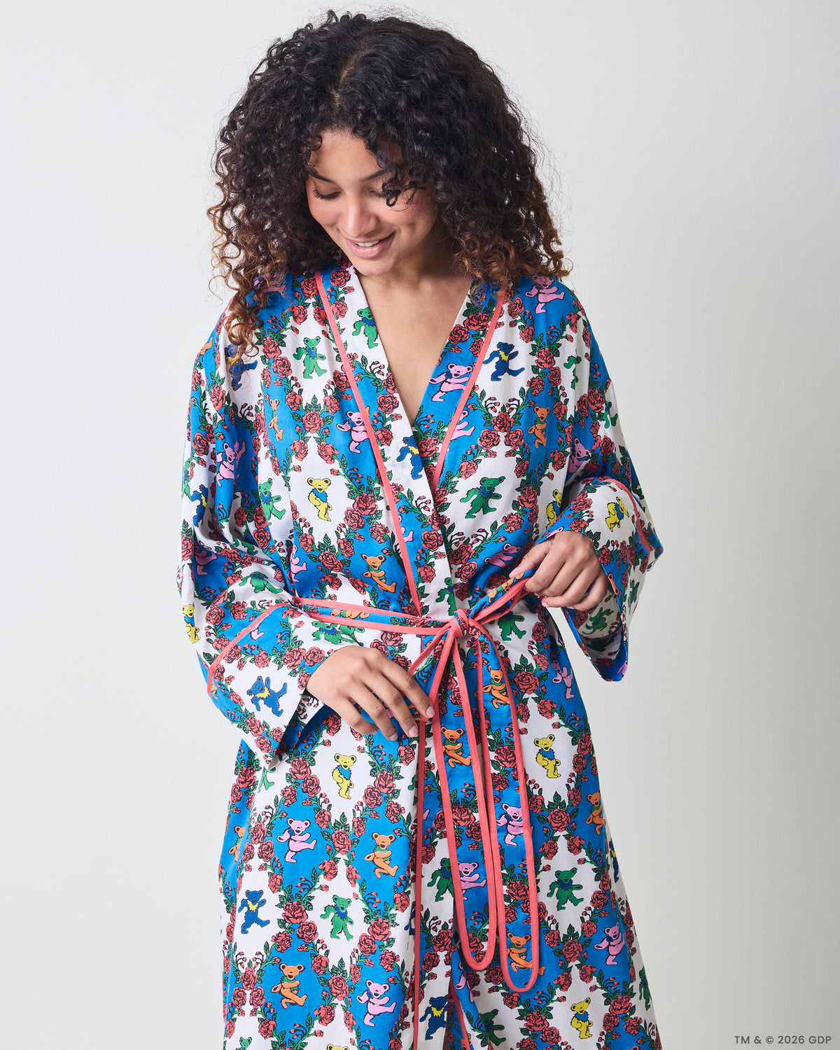 Front view of a long robe with wide sleeves, pink trim, waist ties, and a blue-and-white bear-and-rose print.
