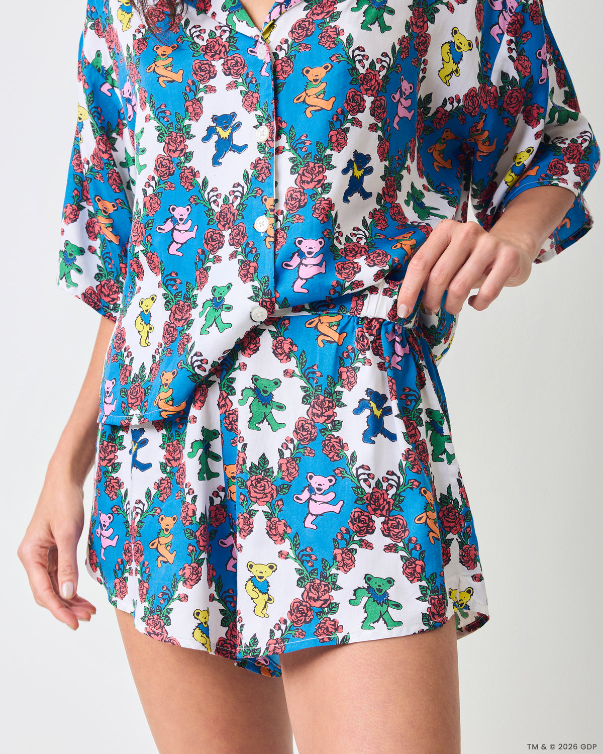 Close front detail of a short-sleeve button-front top and matching shorts with an elastic waist and blue-and-white bear-and-rose print.