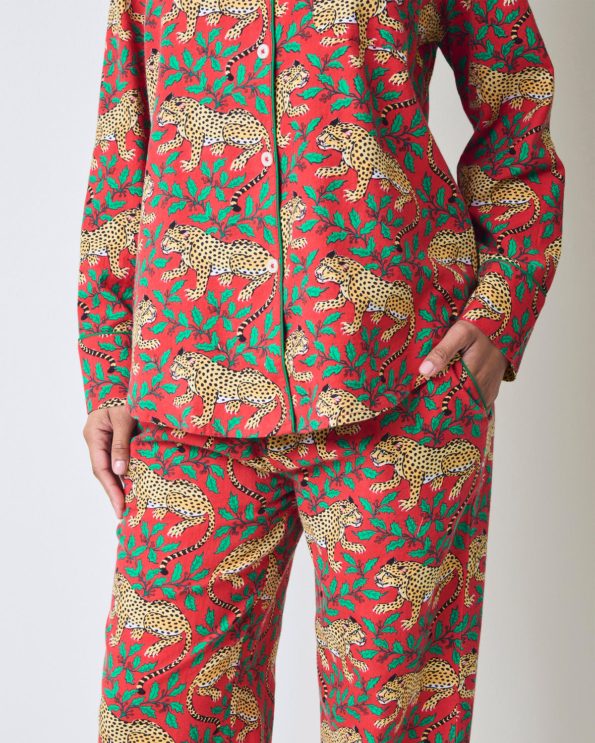 Close-up of the red Winter Holly Bagheera pajama top and matching pants, showing the button front, pocket, and leopard-and-holly print.