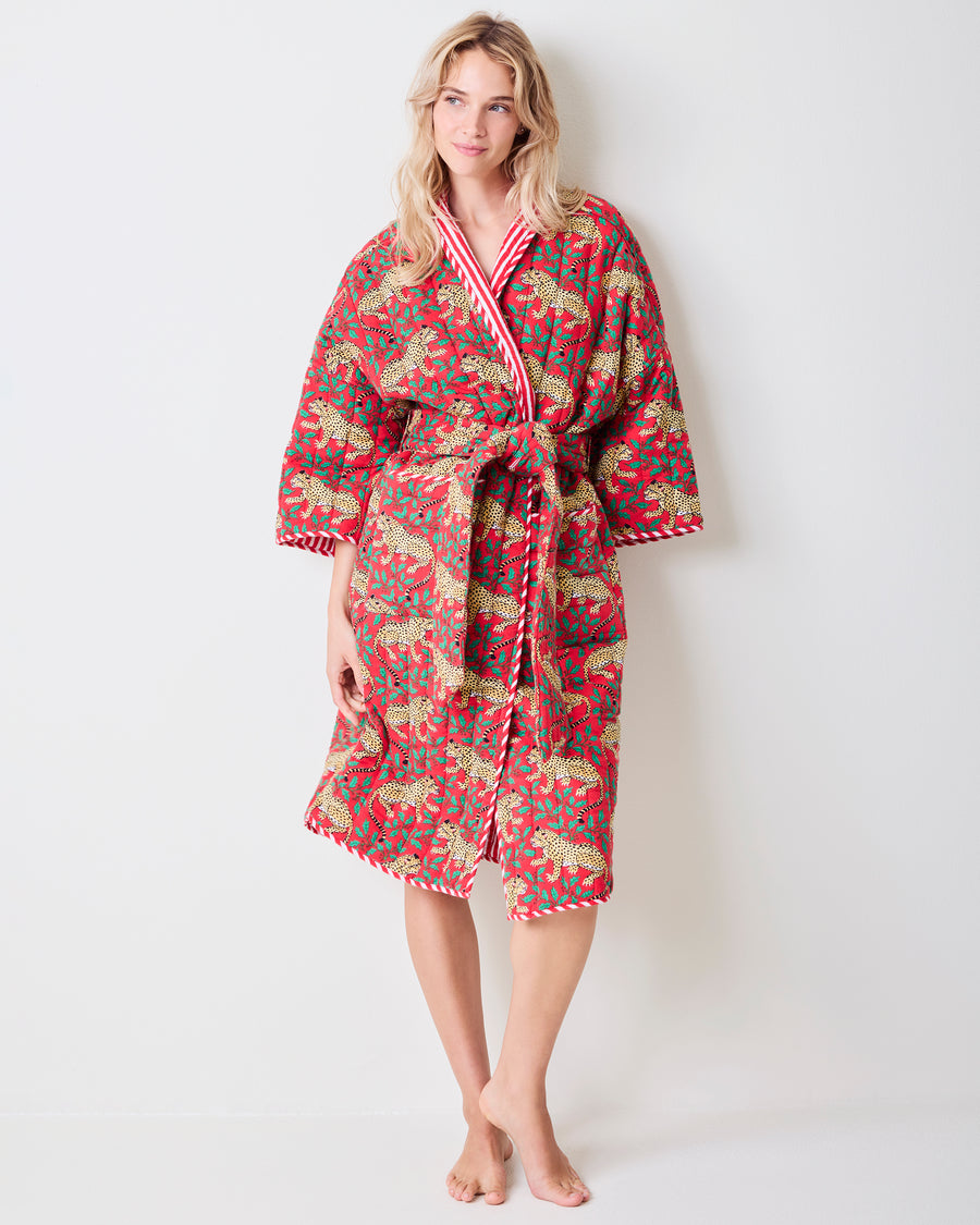 Full-length front view of a red reversible quilted robe with a leopard and green holly print, matching belt, and striped trim.
